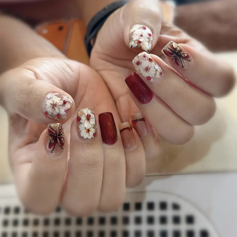 White 3D blossoms and a butterfly with deep red accent nails